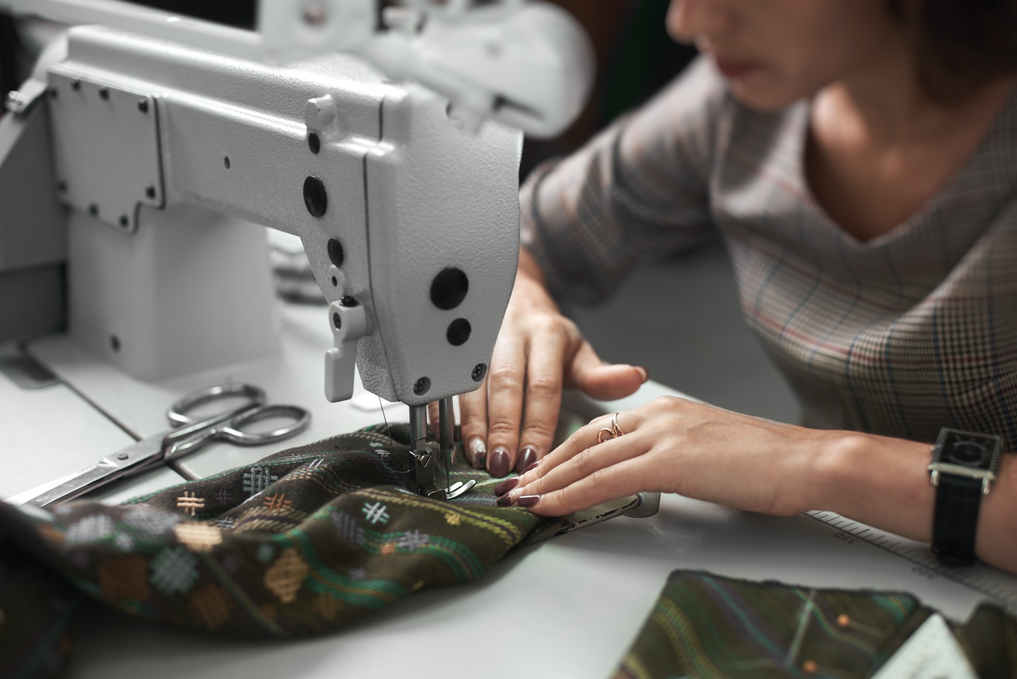 seamstress-working-on-modern-electrical-sewing-machine-making-exclusive-garments-in-fashion-studio-1-1